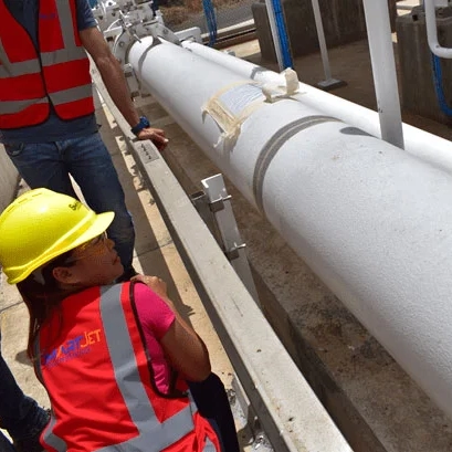 Technicians wearing safety vests and helmets inspecting an industrial pipeline on site