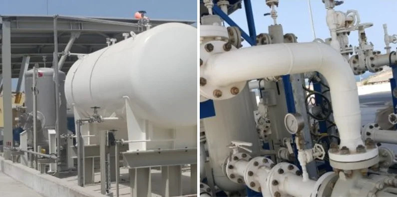Industrial facility featuring large white storage tanks and complex network of interconnected pipelines and valves